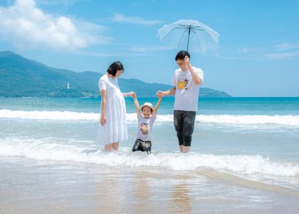 Happy family enjoying a sunny day at Da Nang Beach, Vietnam, playing in the waves.